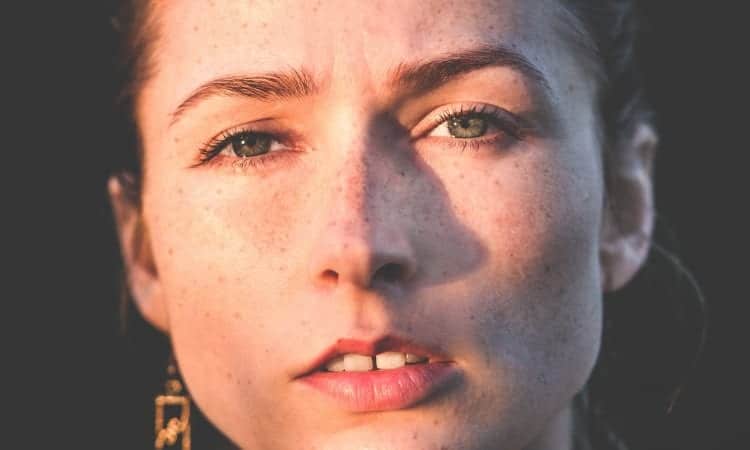 Closeup of a woman's anxious face wondering if her cracked tooth can be fixed at the dentist
