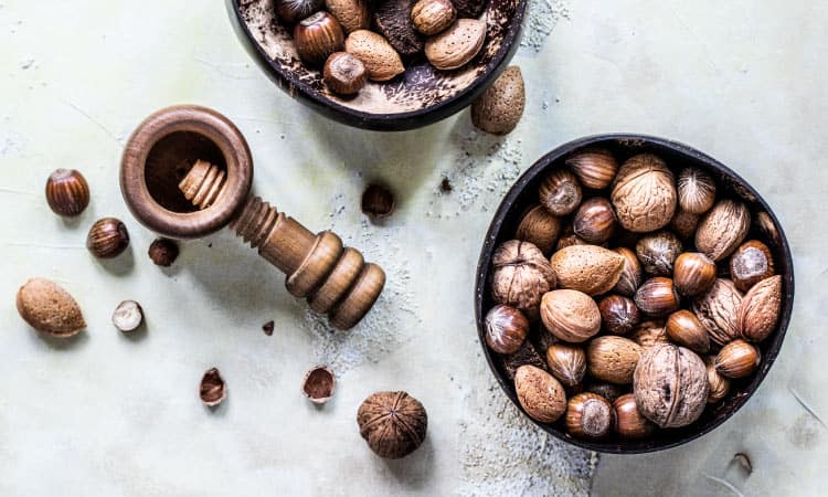 Aerial view of 2 bowls of uncracked nuts, a great holiday treat, next to a nut-cracker