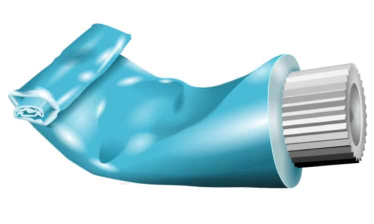 Blue toothpaste tube with white lid is half full with the bottom rolled up a bit against a white background