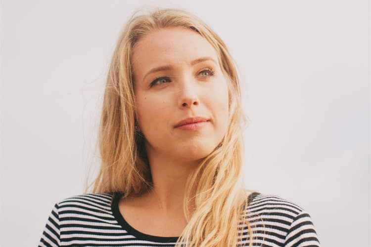 Blonde woman in a striped black and white shirt looks into the distance while considering LANAP to treat her gum disease
