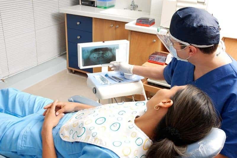 Patient and dentist looking at monitor of dental x-rays